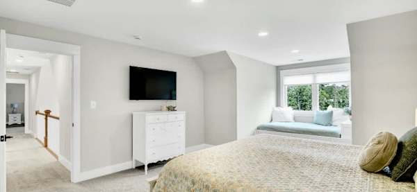 A Smart TV and antique dresser complete the space, blending modern comfort with timeless charm to create a warm, inviting retreat.