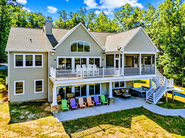 Rear Exterior - Layered decks, a screened porch, a hot tub, and a patio of colorful Adirondack chairs all face the lake.