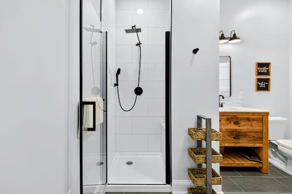 Bunk Bathroom - The walk-in glass shower is finished in clean white tile with a black rainfall and handheld setup, just steps from the vanity.