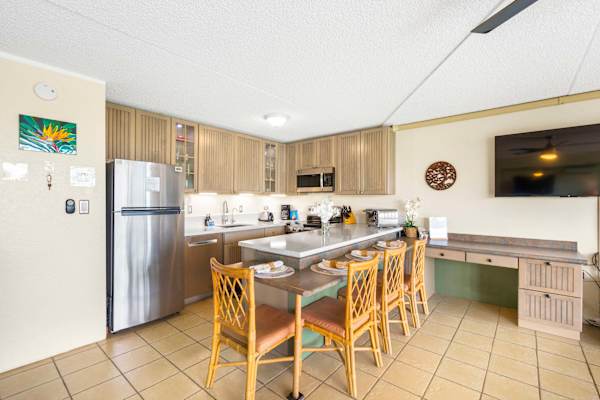Cook up island feasts in your fully equipped kitchen, featuring stainless steel appliances, ample cabinetry, and a multi-level breakfast bar paired with woven chairs