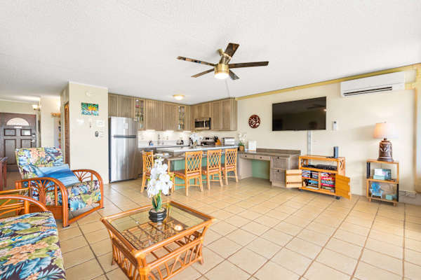 Gather with family and friends in your bright, open-concept living space, complete with a sleeper sofa, a large wall-mounted flat-screen TV, and an adjacent kitchen breakfast bar perfect for casual dining.