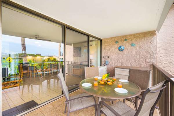 Your balcony offers a wonderful spot to gather, featuring a glass-top dining table and large sliding glass doors that reflect the lush tropical surroundings.