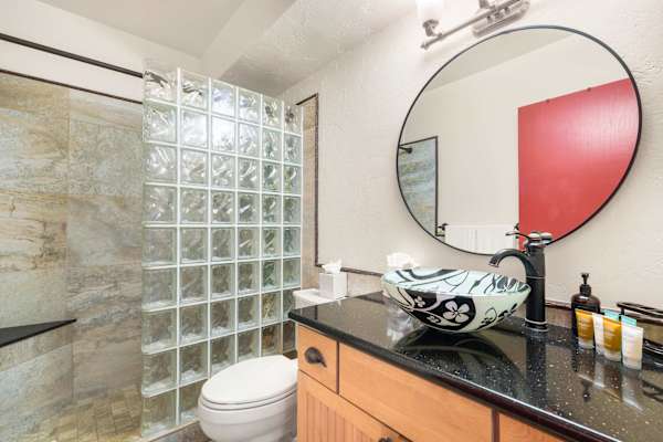Refresh and rejuvenate in this modern bathroom, complete with an artistic vessel sink and a stylish glass-block walk-in shower