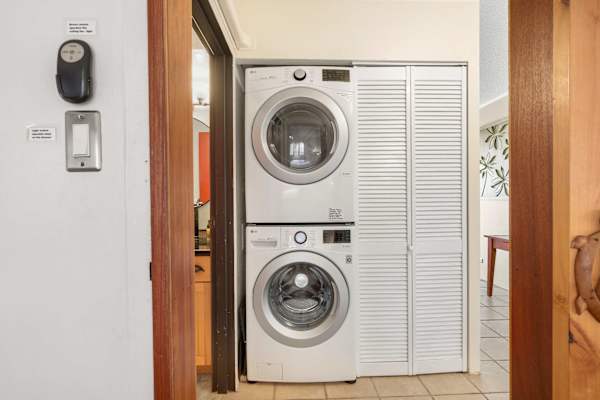 Tucked away for maximum efficiency, this space features a stacked, front-loading washer and dryer alongside a white louvered closet door