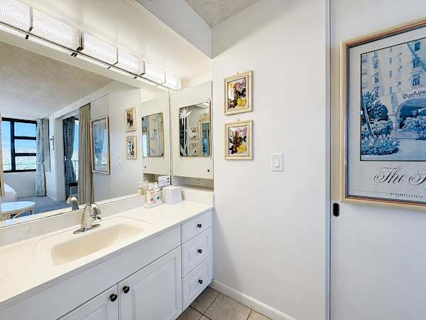 Freshen up in this clean, bright vanity area featuring overhead lighting, ample cabinet storage, and a large mirror that reflects the suite's airy atmosphere