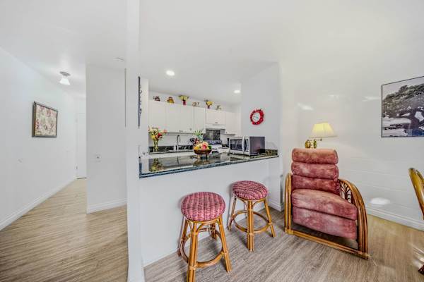 Bright kitchen breakfast bar with wooden stools next to a welcoming hallway entrance. 🍳✨