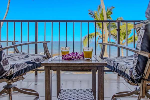 Comfortable balcony seating area with two armchairs and a table overlooking the ocean. 🌴