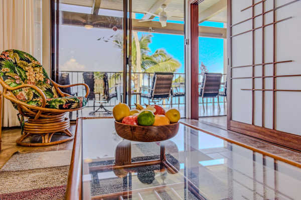 Bright living room layout featuring a glass coffee table with a fresh fruit bowl display. 🍊