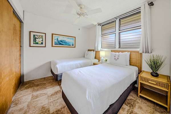 Spacious guest bedroom layout featuring comfortable beds, a nightstand, and framed wall art. 🛏️
