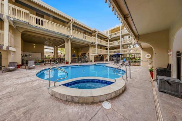Resort swimming pool and circular hot tub setup within the sunny courtyard deck. 🏊♂️