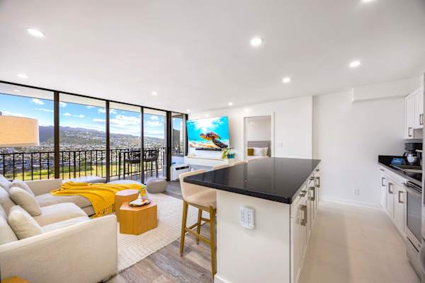 Relax in pure style inside your bright, modern living area, featuring a sectional sofa and floor-to-ceiling glass doors that open up to a private balcony with stunning mountain views.