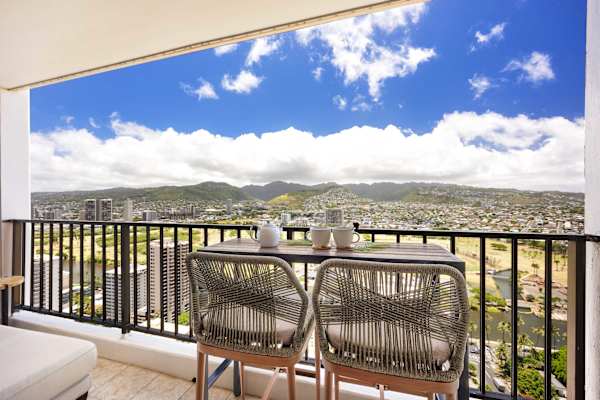 Savor your morning coffee or sunset drinks from your private, high-floor balcony, featuring chic woven bar seating and a breathtaking, panoramic view of the lush mountains and city skyline.