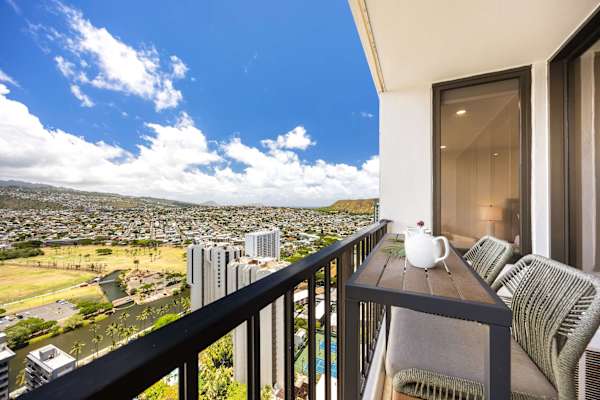 Savor your morning coffee or sunset drinks from your private, high-floor balcony, featuring chic woven bar seating and a breathtaking, panoramic view of the lush mountains and city skyline.