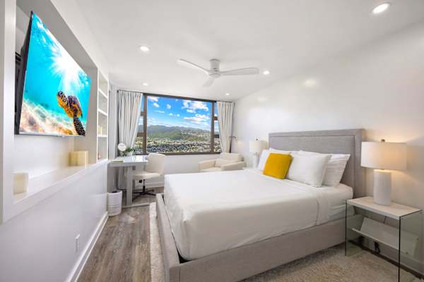 Retreat to your cozy bedroom featuring a queen-size bed, a 50" Smart TV, and a dedicated study desk.