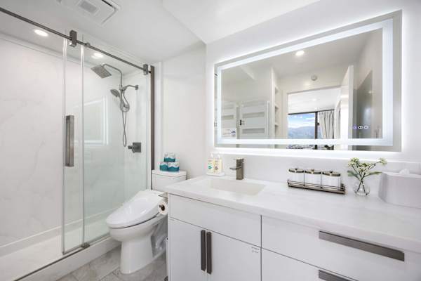 Indulge in a spa-like experience in your own bathroom, with a walk-in shower, a stylish white vanity, and a brilliant LED-backlit mirror.