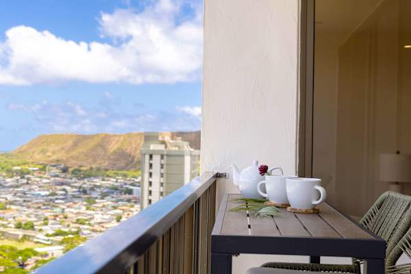 Savor your morning coffee or sunset drinks from your private, high-floor balcony, featuring chic woven bar seating and a breathtaking, panoramic view of the lush mountains and city skyline.