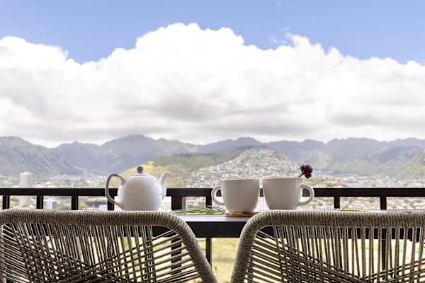 Savor your morning coffee or sunset drinks from your private, high-floor balcony, featuring chic woven bar seating and a breathtaking, panoramic view of the lush mountains and city skyline.