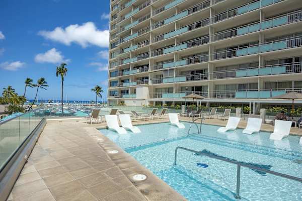 Lounge in luxury at this stunning sun-deck pool, featuring sleek in-water chaise lounges, crystal-clear shallows, and sweeping views of the marina and ocean beyond.