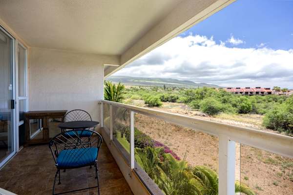 Unwind on this spacious balcony, offering peaceful views of rolling hills and lush green landscapes under bright blue skies.