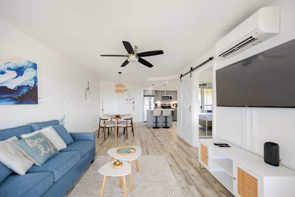 Relax and entertain with ease in your bright, open living room featuring a plush sleeper sofa, 42" flat-screen TV, split-system A/C, and seamless access to dining and kitchen areas.