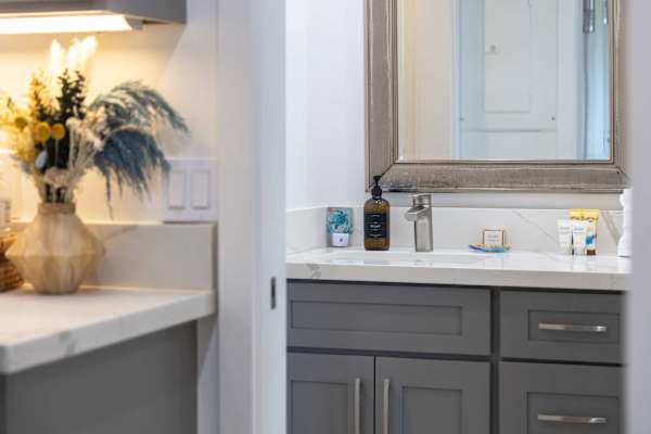 Refresh in style with a modern bathroom vanity featuring sleek grey cabinetry, a quartz countertop, and a framed mirror.