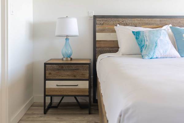 Drift off to sleep in style with rustic wood accents, soft beachy decor, and a cozy bedside reading setup.