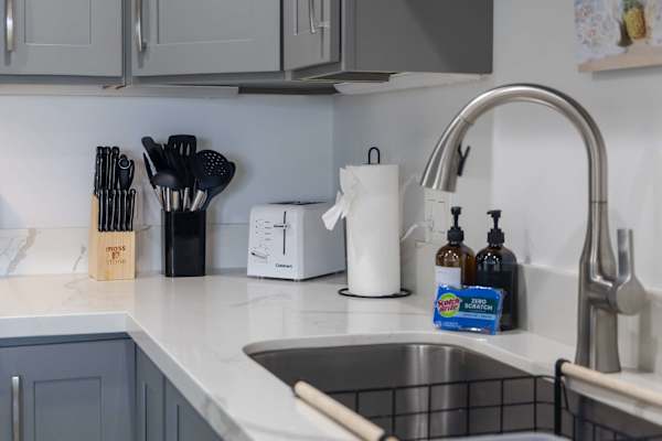 Enjoy effortless prep and cleanup with a modern gooseneck faucet, deep stainless steel sink, and essential kitchen tools right at your fingertips.