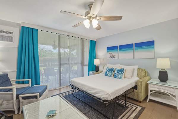 Enjoy flexible sleeping arrangements with a sofa bed set against coastal decor, complete with a ceiling fan, air conditioning, and direct patio access.