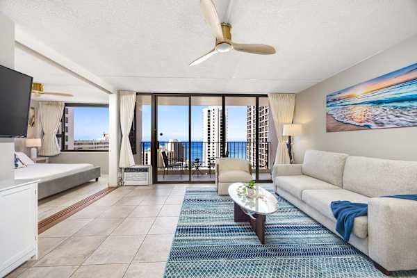 Relax in your light-filled open layout featuring a plush sleeper sofa, coastal-inspired decor, a 50" smart TV, and seamless access to both the ocean-view balcony and adjacent bedroom suite.