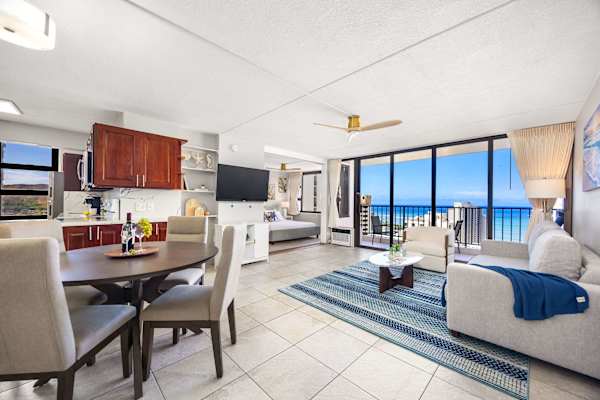 This expansive open-concept suite seamlessly combines dining, living, and sleeping areas with a full kitchen and floor-to-ceiling glass doors opening to sweeping ocean views.