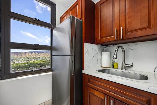 Your kitchen area includes a refrigerator, a sink, wooden cabinets, and a window with Diamond Head views.
