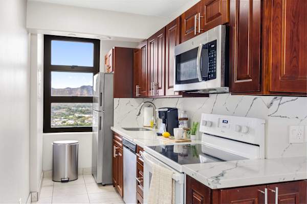Your kitchen features warm wooden cabinets, a microwave, an electric stove, a sink, and a large window looking out at Diamond Head Mountain.