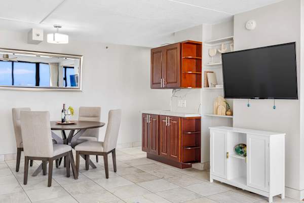This space features a round dining table with 4 chairs, wooden cabinets, and a wall-mounted 50" TV.