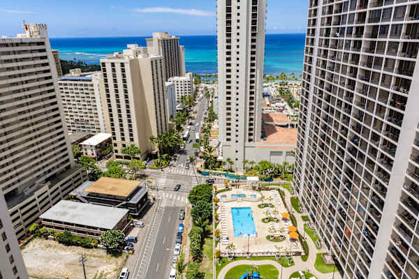 Take in breathtaking high-rise views of the vibrant city streets below, complete with a sparkling outdoor pool deck and the turquoise ocean on the horizon.