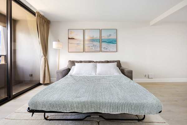 Enjoy extra sleeping space in your sofa bed, perfectly situated next to bright sliding glass doors and soothing coastal artwork.