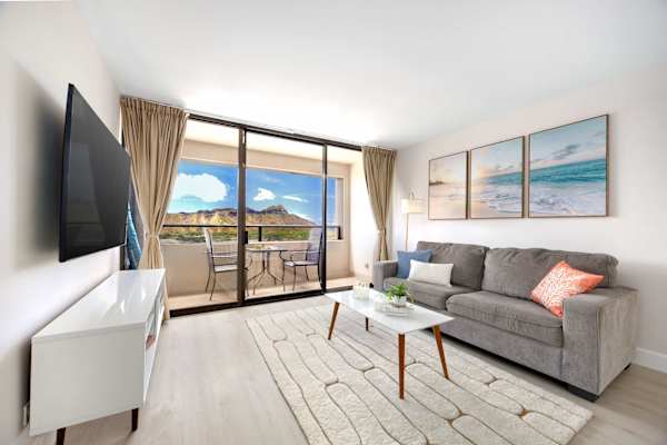 Relax in your bright, coastal-inspired living room w/ 65" smart TV, plus boasting floor-to-ceiling glass doors that frame stunning views of Diamond Head.
