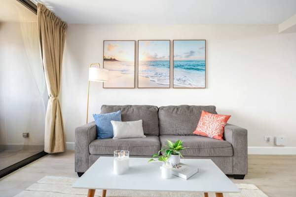 Unwind on your plush sofa in this cozy seating area, accented by tranquil beach wall art and throw pillows.