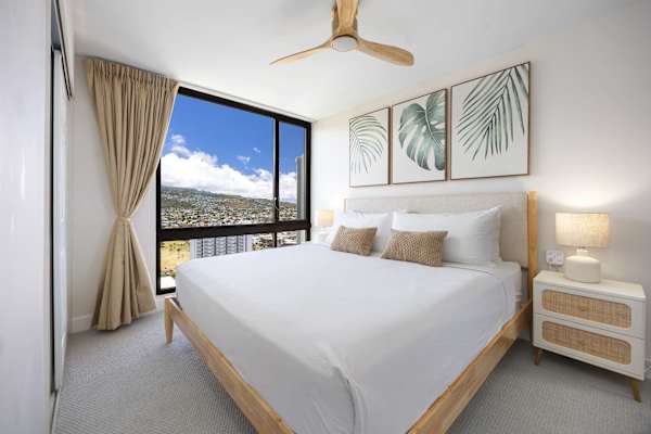 Wake up to stunning elevated views in your serene, tropical-inspired king bedroom styled with warm wooden tones and fresh linens.