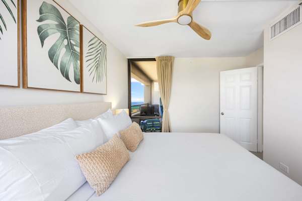 Retreat to your serene, airy bedroom featuring a plush king bed adorned with tropical artwork and direct access to your private balcony.