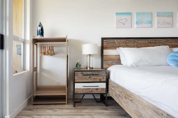 Keep organized with an open clothing rack, an iron, and a matching bedside table equipped with a table lamp.