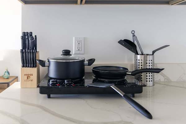 Prepare delicious home-cooked meals with ease using a portable cooktop fully stocked with cookware, utensils, and a knife block set.
