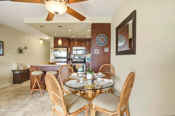 Share meals together in your dining area featuring a glass-top table, woven wicker chairs, and seamless access to the adjacent breakfast bar and kitchen.