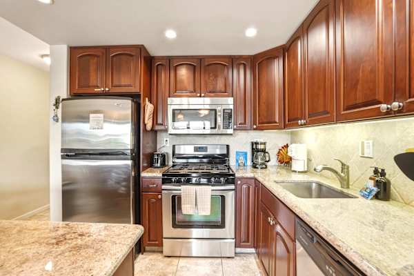 Prepare delicious vacation meals in this fully equipped kitchen boasting rich wood cabinetry, modern stainless steel appliances, and sleek granite countertops.