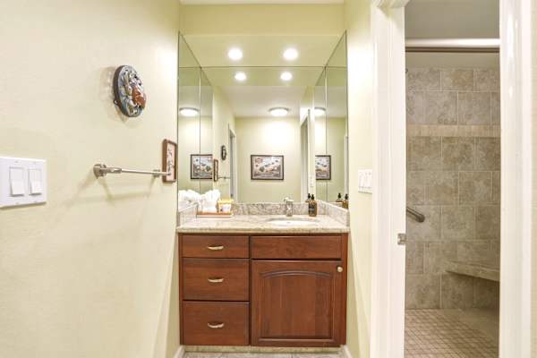 Refresh and unwind in your well-appointed bathroom featuring a wood vanity with plenty of storage, a mirror, and an adjacent tiled walk-in shower.