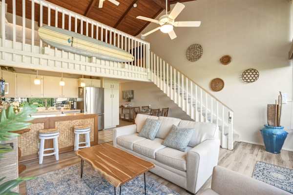 Experience seamless open-concept living with high vaulted wood ceilings, a pull-out sleeper sofa, and a charming loft bedroom featuring decorative island flair.