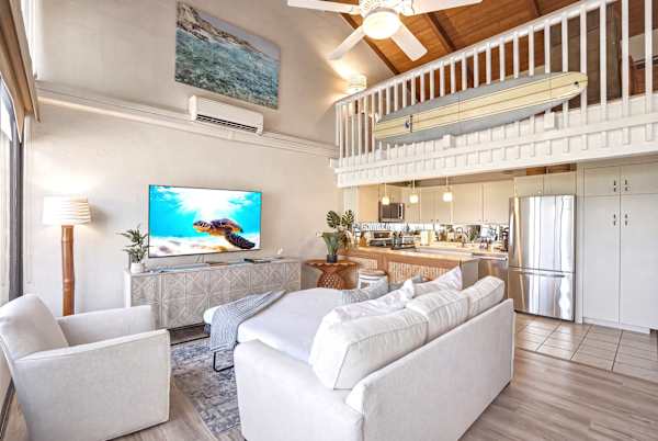 Your spacious open-concept living area features soaring wood ceilings, a 58" TV, a pull-out sleeper sofa, and an upper-level loft bedroom.