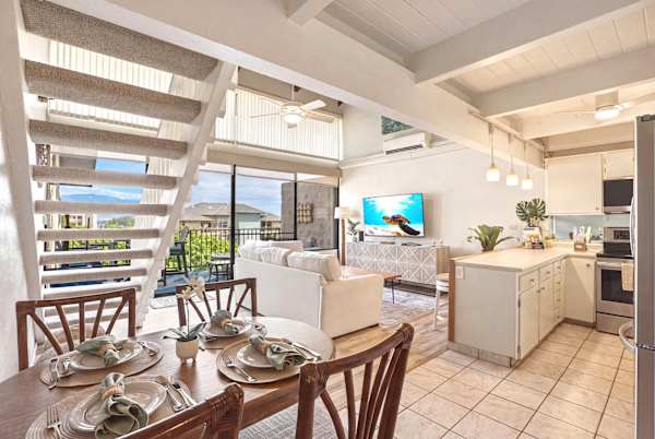 This perspective captures the entire main floor layout, seamlessly connecting the cozy dining area and kitchen to the bright living room and stairs leading up to the loft bedroom.