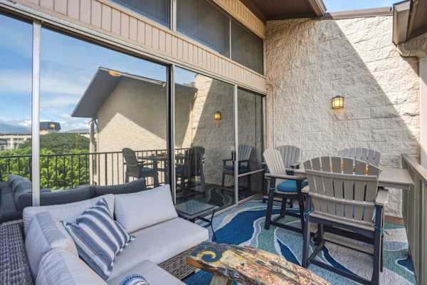 Step outside onto your spacious, private lanai featuring comfortable lounge seating, an outdoor dining setup, and vibrant, coastal-inspired decor perfect for relaxing in the fresh breeze.