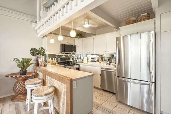 Bright and welcoming, your well-appointed kitchen features stainless steel appliances, warm woven-wood accents, and bar seating underneath elegant pendant lighting.
