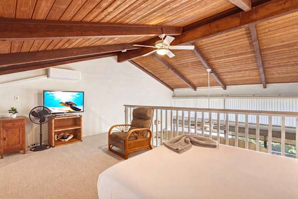 Your charming loft bedroom offers vaulted wood-beam ceilings, a dedicated TV, air conditioning, and a ceiling fan for a cool, relaxing space.